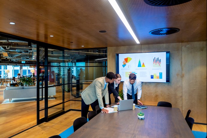 co-workers using a laptop in a boardroom